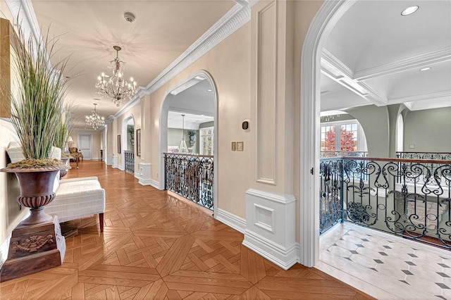 corridor with a chandelier, light parquet floors, and crown molding