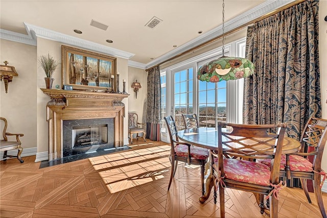 dining room featuring ornamental molding, a high end fireplace, and light parquet flooring