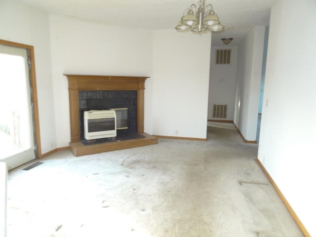 unfurnished living room with heating unit, a fireplace, carpet floors, and a notable chandelier