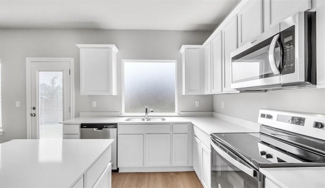 kitchen with a healthy amount of sunlight, sink, white cabinets, and stainless steel appliances