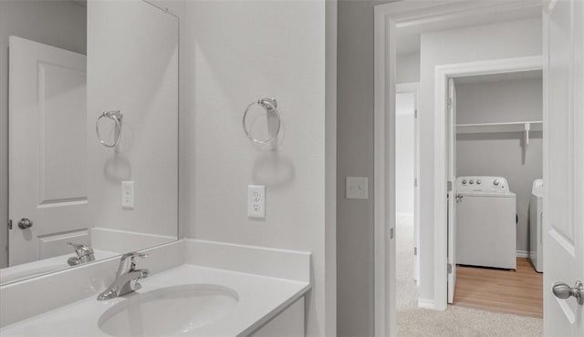 bathroom with hardwood / wood-style floors, vanity, and separate washer and dryer