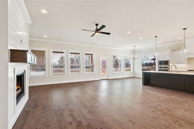 unfurnished living room with crown molding, sink, ceiling fan, and dark hardwood / wood-style floors