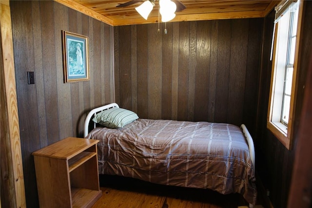 bedroom with wood-type flooring, wooden ceiling, ceiling fan, and wooden walls