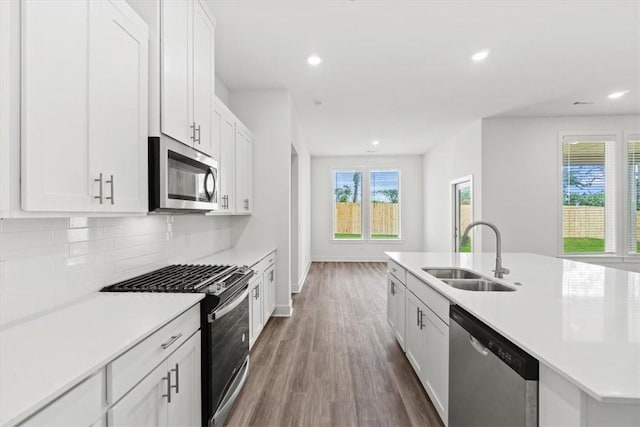 kitchen with a sink, tasteful backsplash, stainless steel appliances, white cabinets, and light countertops