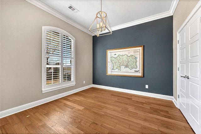 empty room with crown molding, a chandelier, and hardwood / wood-style flooring