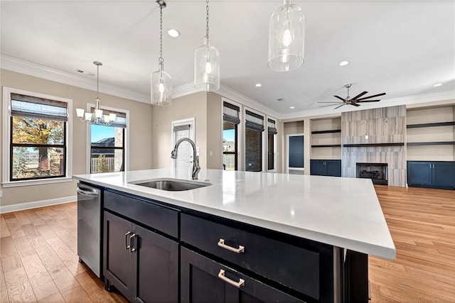 kitchen featuring a kitchen island with sink, ceiling fan with notable chandelier, sink, light hardwood / wood-style flooring, and ornamental molding