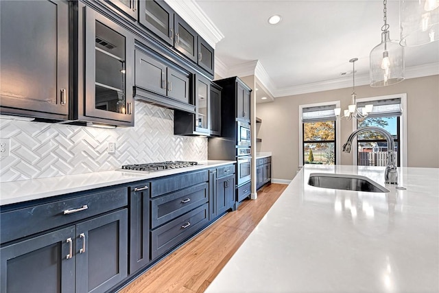 kitchen with light wood-type flooring, decorative light fixtures, crown molding, and sink