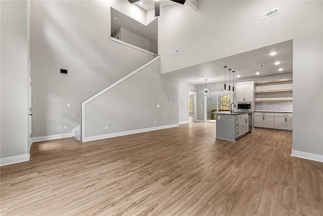 117 Kinross Dr, Bella Vista, AR 72715 - unfurnished living room featuring light wood-style floors, a ceiling fan, a towering ceiling, and recessed lighting
