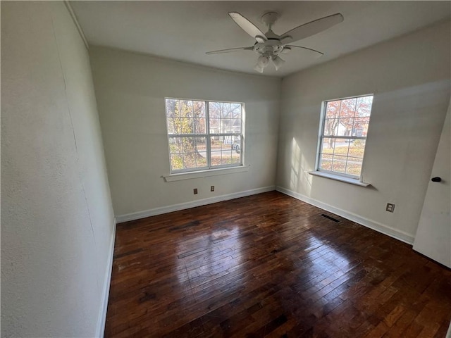 empty room featuring ceiling fan, dark wood-type flooring, and a healthy amount of sunlight