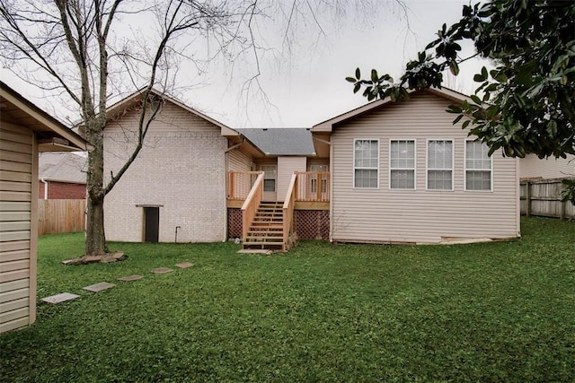 rear view of house with a yard, fence, a deck, and stairs