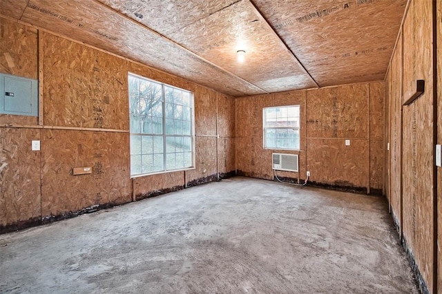 unfurnished room featuring a wall mounted AC and electric panel