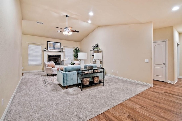 living room with a fireplace, lofted ceiling, visible vents, ceiling fan, and wood finished floors