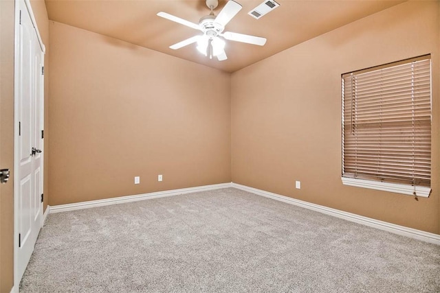 carpeted spare room featuring ceiling fan, visible vents, and baseboards