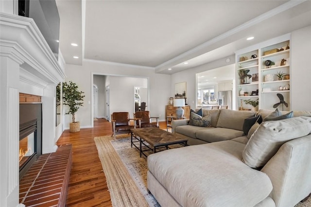 living room featuring a brick fireplace, crown molding, and hardwood / wood-style flooring