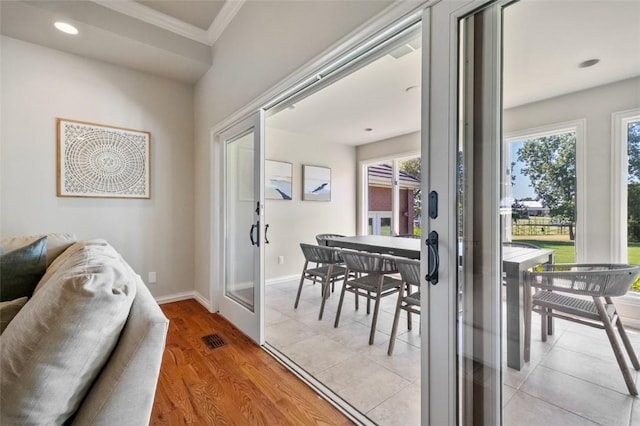 doorway featuring crown molding, a healthy amount of sunlight, and light wood-type flooring