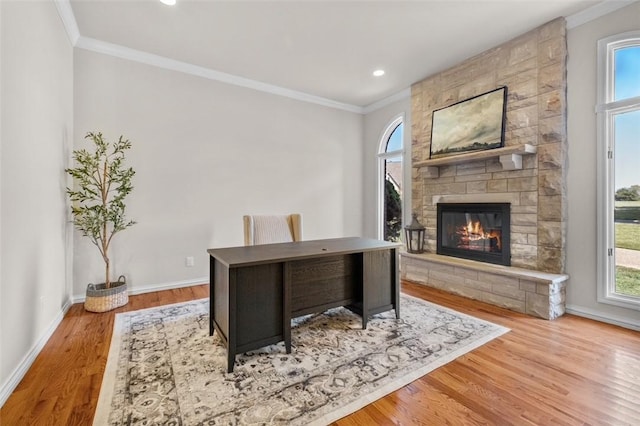 office area with light hardwood / wood-style flooring, a stone fireplace, and crown molding