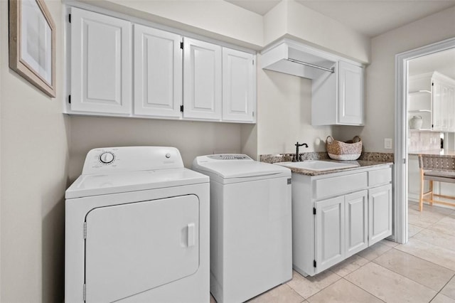 clothes washing area featuring cabinets, light tile patterned floors, washer and clothes dryer, and sink