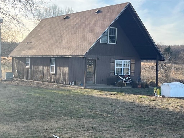 rear view of property featuring central air condition unit and a lawn