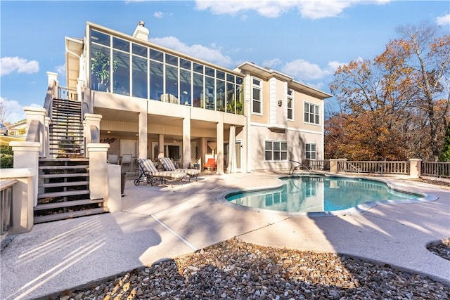 rear view of property with a fenced in pool and a patio area