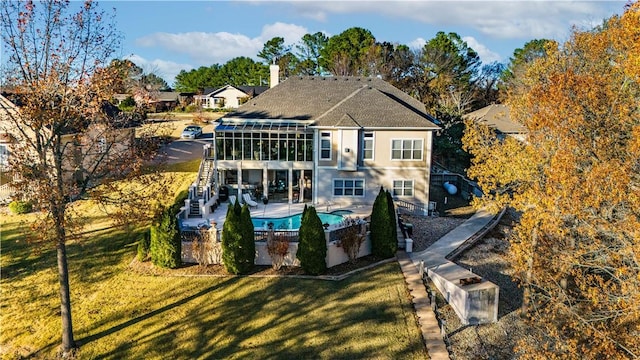 rear view of property featuring a lawn, a sunroom, and a patio area