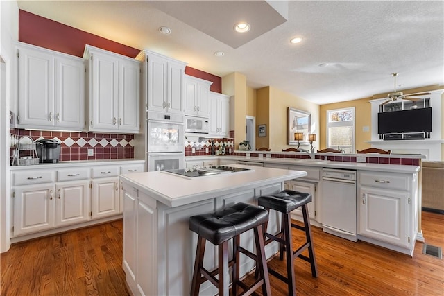 kitchen with white cabinets, a breakfast bar, a kitchen island, and kitchen peninsula