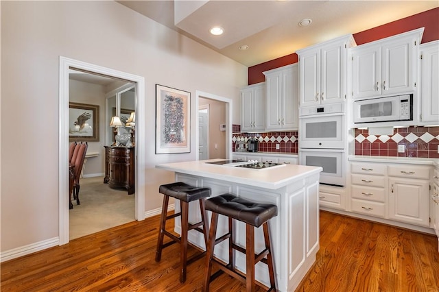 kitchen with decorative backsplash, white appliances, white cabinetry, and a kitchen island