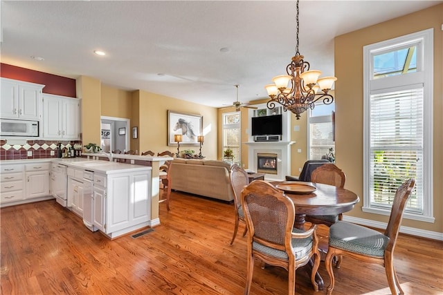 kitchen with white cabinets, white appliances, hanging light fixtures, and backsplash