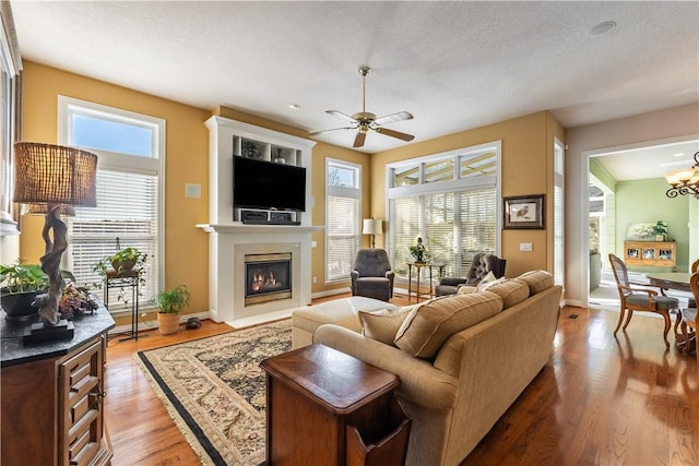 living room featuring ceiling fan, a textured ceiling, and light wood-type flooring