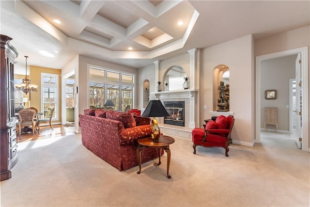 living room with light carpet, a tile fireplace, coffered ceiling, an inviting chandelier, and beamed ceiling