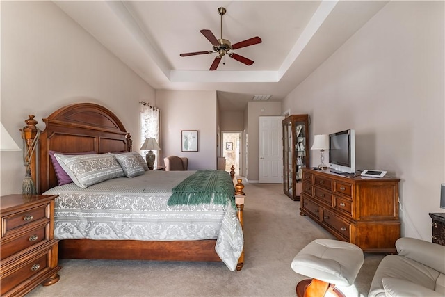 bedroom featuring a raised ceiling, ceiling fan, and light carpet