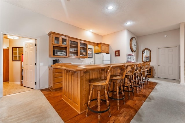 kitchen with white refrigerator, hardwood / wood-style flooring, a kitchen island, and a breakfast bar area