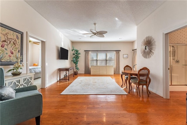 living room featuring ceiling fan, a textured ceiling, and hardwood / wood-style flooring