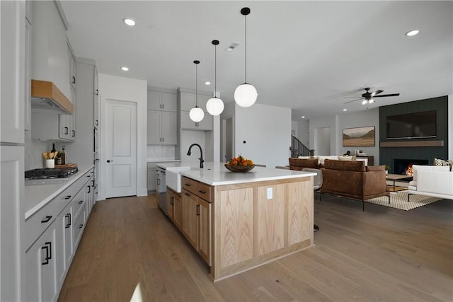4201 88th St, Bentonville, AR 72718 - kitchen with light wood finished floors, light countertops, a ceiling fan, a sink, and stainless steel gas cooktop