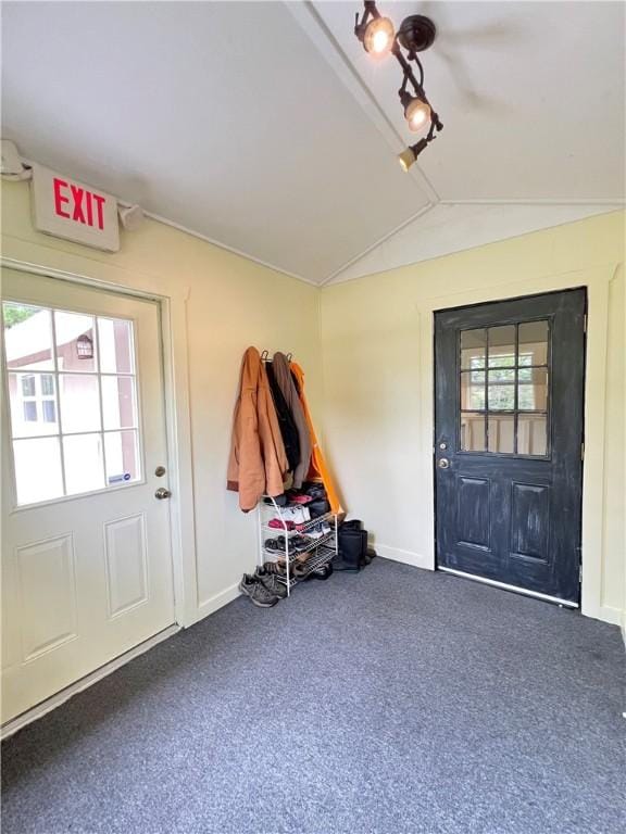 foyer with dark colored carpet, vaulted ceiling, and plenty of natural light