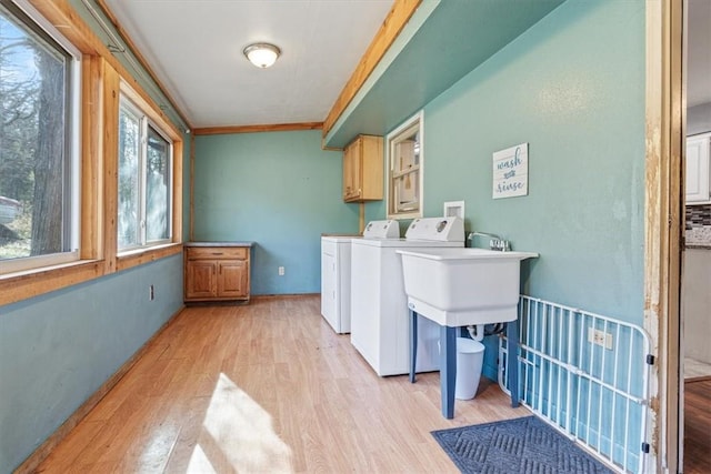 laundry room featuring cabinet space, light wood-style flooring, ornamental molding, independent washer and dryer, and a sink