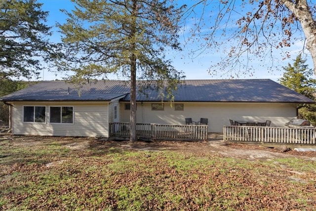 back of house featuring metal roof and a deck