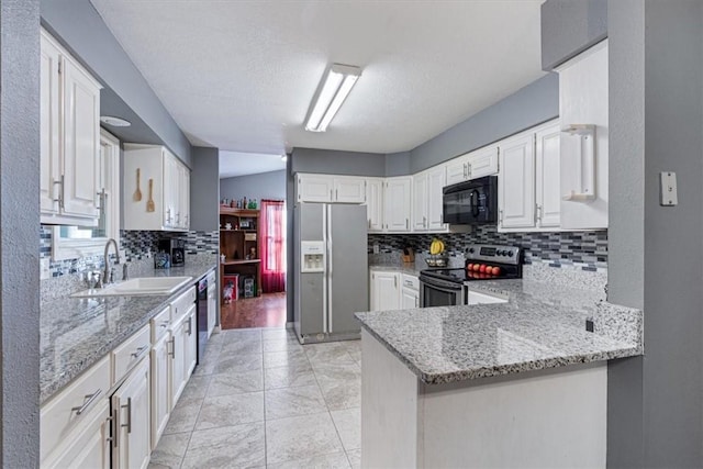 kitchen featuring light stone counters, a sink, decorative backsplash, and black appliances