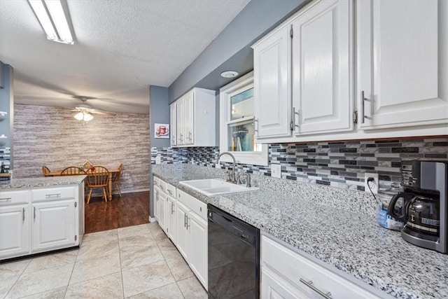 kitchen with dishwasher, light stone counters, a sink, and white cabinetry