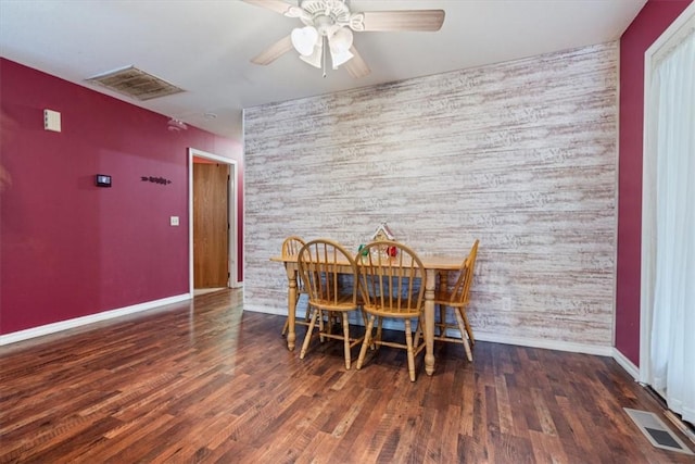 dining area with an accent wall, wood finished floors, and visible vents