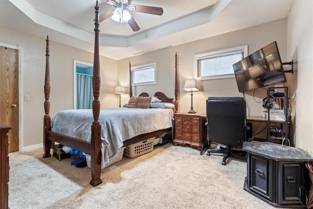 bedroom with a ceiling fan, a tray ceiling, baseboards, and carpet