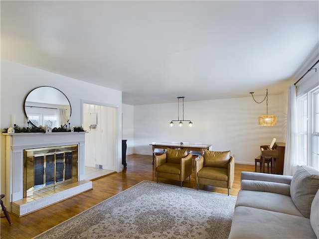 living room featuring hardwood / wood-style flooring, a notable chandelier, and a tiled fireplace