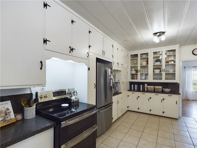 kitchen with white cabinets, light tile patterned flooring, ornamental molding, and appliances with stainless steel finishes