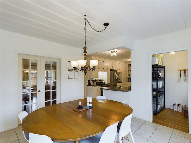 dining space with french doors, light hardwood / wood-style floors, and a notable chandelier