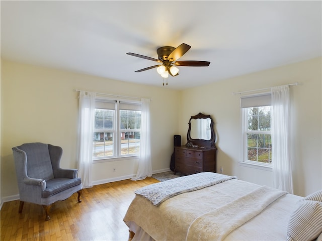 bedroom with ceiling fan, light hardwood / wood-style flooring, and multiple windows