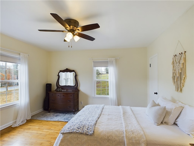 bedroom with multiple windows, ceiling fan, and hardwood / wood-style floors