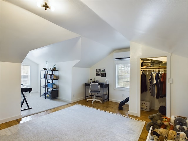 home office featuring lofted ceiling, wood-type flooring, and a wall mounted air conditioner