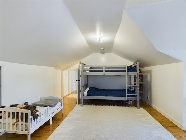 bedroom with hardwood / wood-style floors and lofted ceiling