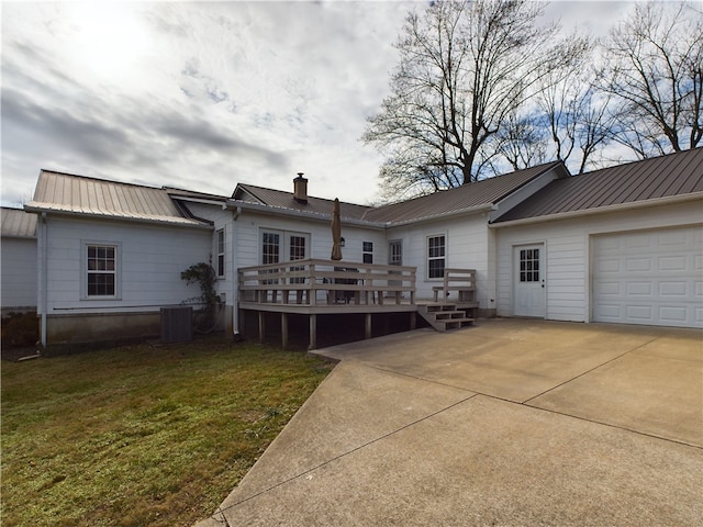 rear view of house with a lawn, a garage, a wooden deck, and central AC