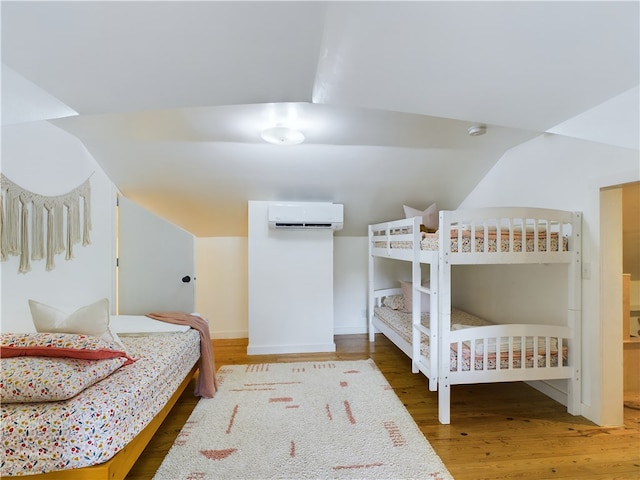 bedroom featuring a wall mounted air conditioner, dark hardwood / wood-style floors, and lofted ceiling