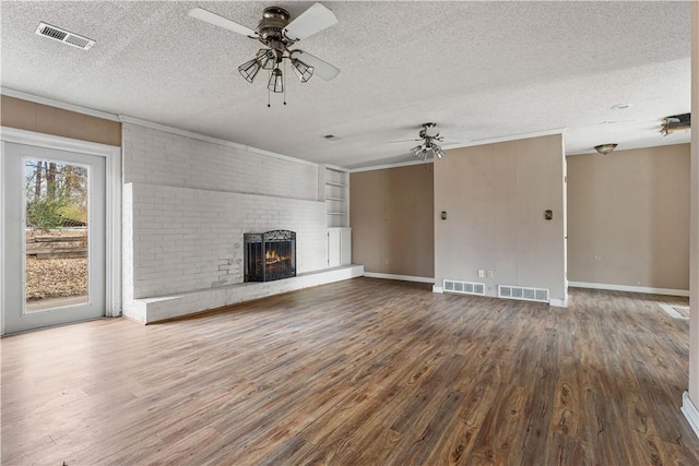 unfurnished living room featuring ceiling fan, wood-type flooring, a textured ceiling, and a brick fireplace